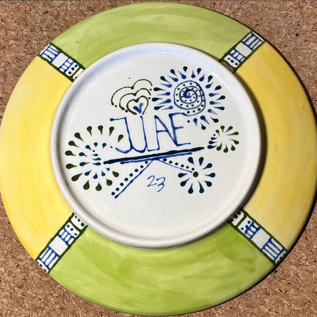 Portfolio Ceramic - Abstract Sunflower Plate bottom. Julis sign with some extra paintings. The Colors: yellow, light green, black and dark blue.